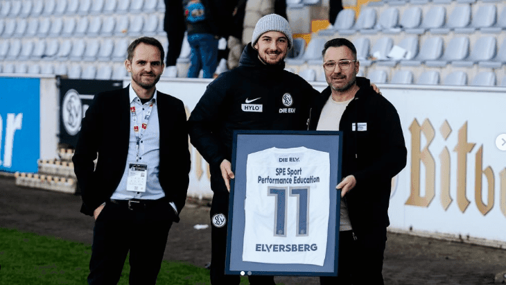 Übergabe eines gerahmten Elversberg-Trikots mit dem Aufdruck „SPE Sport Performance Education“ im Stadion